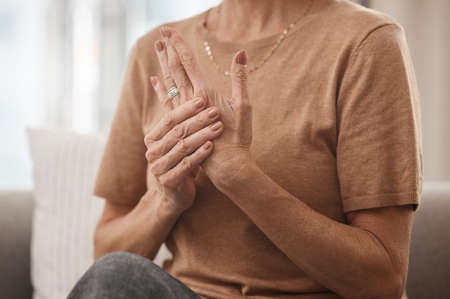 Help, my joints hurt. Shot of an unrecognisable woman experiencing pain in her hand at home.の写真素材