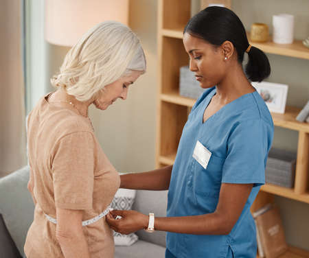 Its never too late to start living healthy. Shot of a doctor using a measuring tape on a senior womans stomach during a consultation at home.の写真素材