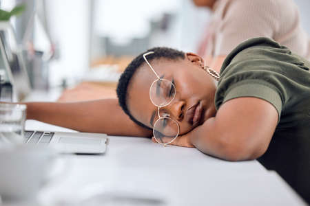 Perhaps a nap will get me in the creative zone. Shot of a young businesswoman sleeping at her desk in an office.の写真素材