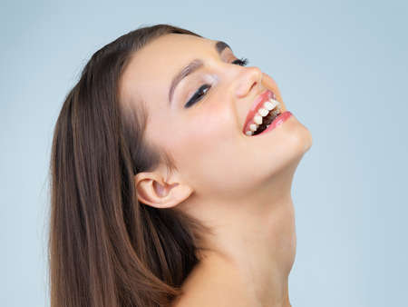 Laughter, the great beauty enhancer. Studio shot of a beautiful young woman posing against a blue background.の写真素材