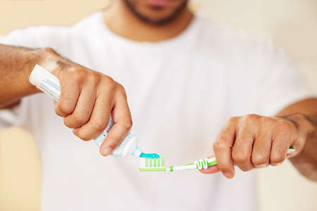 The right toothpaste makes all the difference. Cropped shot of a man putting toothpaste on his toothbrush.の写真素材