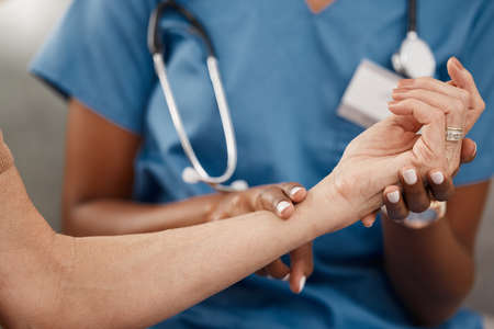 Keep your finger on the pulse of your health. Shot of a doctor examining a senior womans pulse during a consultation at home.の写真素材