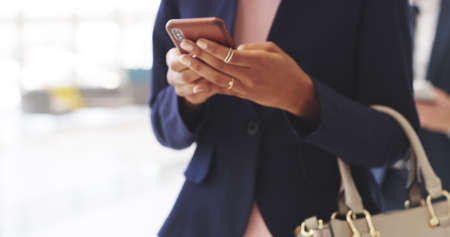 Checking her schedule for the seminar. 4k video footage of an unrecognizable businesswoman using a cellphone in the convention centre.の写真素材