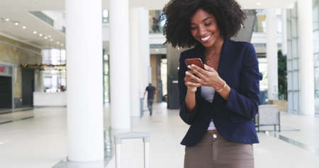 Make winning a habit. 4k video footage of a young businesswoman receiving good news on her smartphone.の写真素材