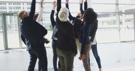 Their team spirit stays high. 4k video footage of a group of businesspeople joining their hands in a huddle and dancing together.の写真素材