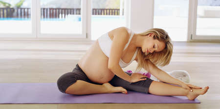 Staying limber for the baby. Full length shot of an attractive young pregnant woman warming up...