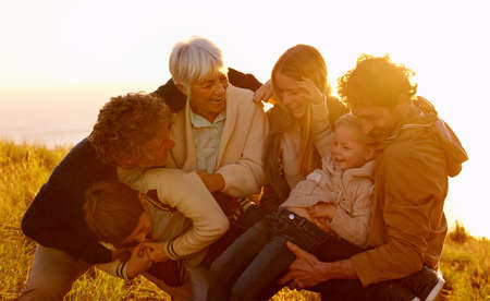Having fun and making memories. A cropped shot of a family having fun on their sunset walk up a grassy hill.の写真素材