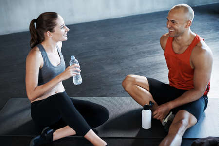 Training to become fighting fit. Shot of a man and woman taking a break after a workout at the gym.