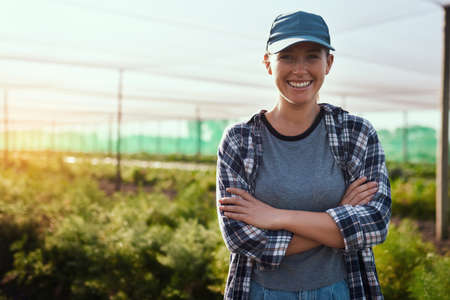 I run a fruitful farm. Cropped portrait of an attractive young female farmer standing with her arms crossed while working on the farm.の写真素材