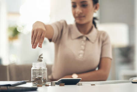 Practice being a savvy saver. Closeup shot of an unrecognisable businesswoman filling a glass jar...