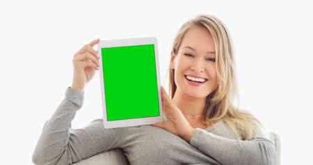 The perfect display for your website. Shot of an attractive young woman holding up a tablet at home.の写真素材
