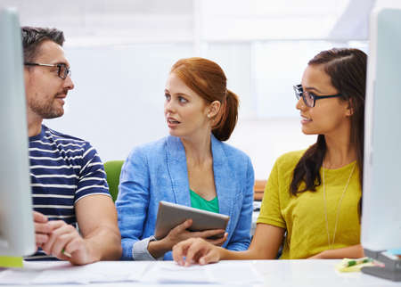 Is it really due now. Three coworkers discussing deadlines at their desk at work.