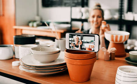 Showing the insights to my fans. Cropped shot of an attractive mature woman using her cellphone to record her pottery process for her blog.の写真素材