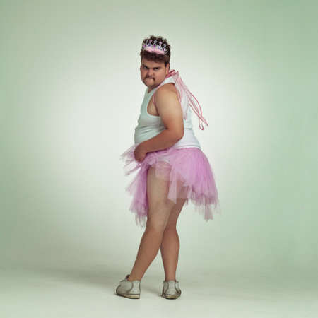 Sexy legs. An overweight man comically dressed-up in a pink fairy costume showing his leg off.の写真素材