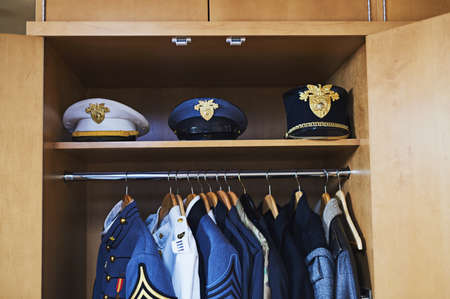 Not every hero wears a cape. Shot of various military jackets and hats hanging in a closet.の写真素材