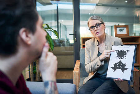 Gaining access into the subconscious mind. Shot of a mature psychologist conducting an inkblot test with her patient during a therapeutic session.の写真素材
