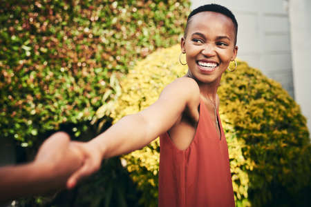 Lets run away from it all. Cropped shot of a happy young woman pulling her partner by the hand.の写真素材
