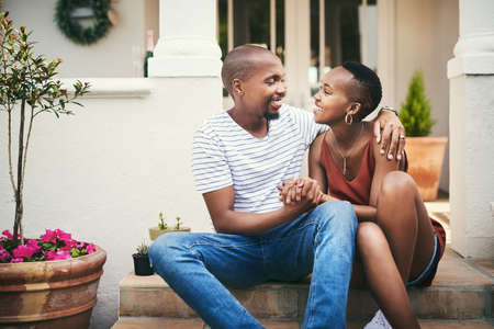Home is wherever you are, babe. Shot of an affectionate couple sitting on their front door steps.の写真素材