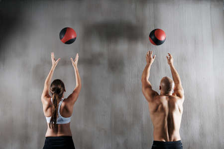 Training to become fighting fit. Shot of a young man and woman working out with medicine balls at the gym.の写真素材