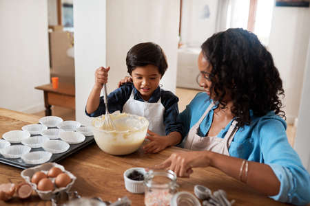 Baking is a win-win activity. Shot of a woman baking at home with her young son.の写真素材