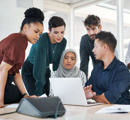 Making troubleshooting a team task. Shot of a group of businesspeople using a laptop during a...