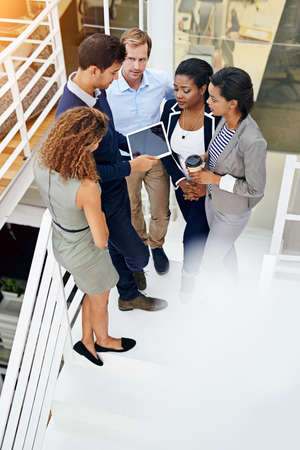 Everyone is in on this project. Shot of a group of coworkers having a meeting in a stairwell in a...