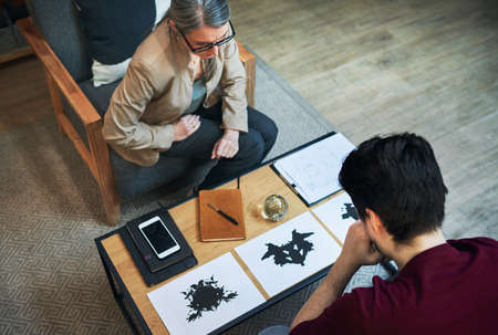 A way to scan the subconscious. Shot of a mature psychologist conducting an inkblot test with her patient during a therapeutic session.の写真素材