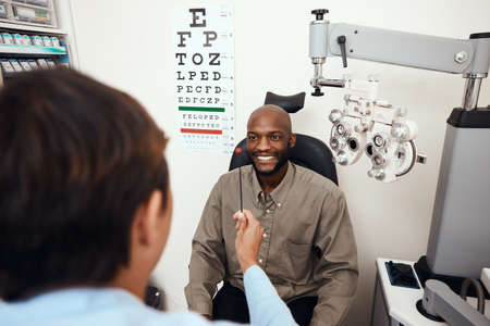 One step away from better eyesight. Shot of a young man having an eye test conducted by an optometrist.の写真素材