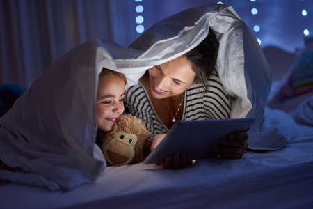 Can we read another one, Mom. Cropped shot of an attractive young woman reading her daughter a...