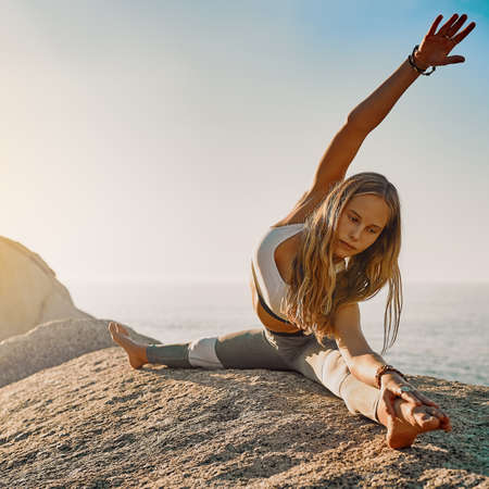 Stay patient and trust your journey. Shot of an athletic young woman practicing yoga on the beach.の写真素材