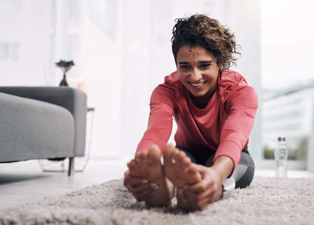No better way to warmup. Shot of a young woman doing some warmup exercises on the floor at home.