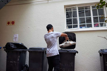 Doing the responsible thing. Shot of a young man putting newspaper in the bin to be recycled.の写真素材
