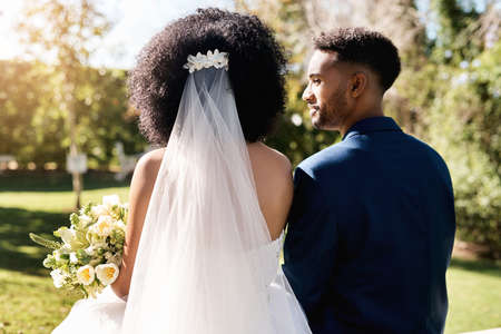 Lets grow old together. Rearview shot of a newlywed young couple standing together outdoors on their wedding day.の写真素材