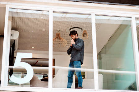 I hope this works out. Shot of a young businessman looking anxious while standing at a glass wall in...