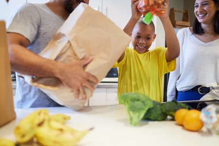 Helping the family to make supper. Shot of a family unpacking the groceries in the kitchen at home.の写真素材
