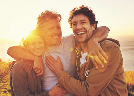 Friends uplift the soul. Portrait of three friends standing on a hill top at sunset.の写真素材