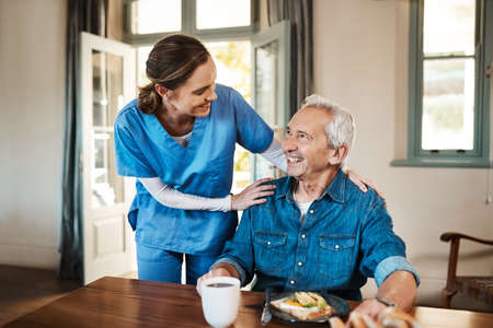 Everything to your satisfaction. Shot of a young nurse checking up on a senior man during breakfast at a nursing home.の写真素材