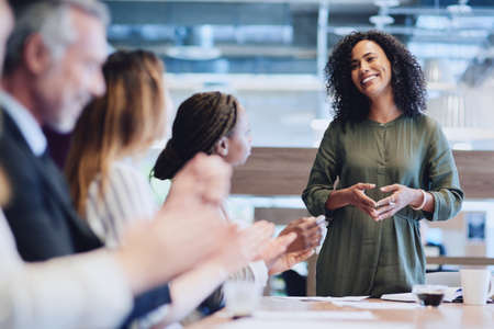 I couldnt have done it without all of you. Cropped shot of a group of businesspeople applauding a colleague while sitting in the boardroom during a meeting.の写真素材