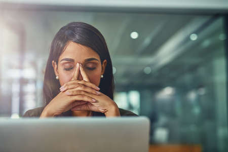 Feeling drained from all her efforts. Shot of a young businesswoman looking stressed out while...