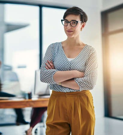 Opportunities just keep rolling in for me. Portrait of a confident young creative standing in an office.の写真素材