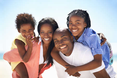 Our parents are so strong. An african-american family enjoying a day at the beach together.の写真素材