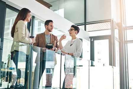 Time for a quick catch up in the office. Shot of a group of colleagues talking together in a large...