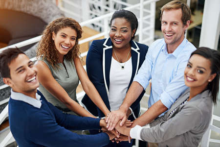 Putting everything in for the team. Portrait of a group of coworkers standing with their hands...