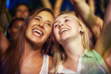 Having the time of their lives. Young girls in an audience enjoying their favourite bands performance.の写真素材