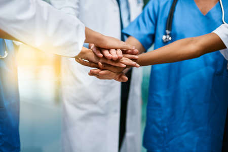 In it to saves lives together. Shot of a group of unrecognisable medical practitioners joining their hands together in unity.の写真素材