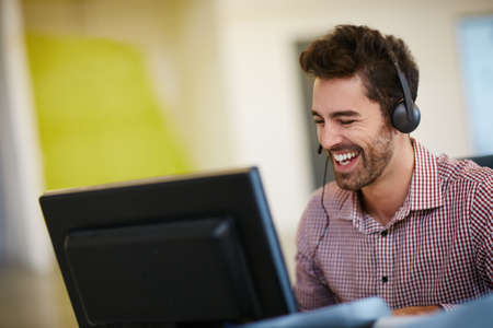 Quality is the best business plan. Shot of a friendly young call centre agent sitting at his desk.