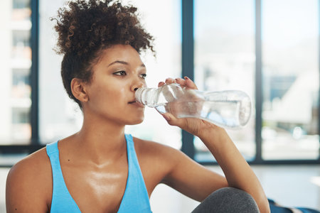 Taking some liquids on board. Cropped shot of a young woman drinking some water after yoga class.