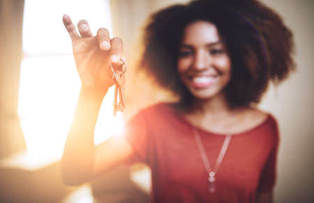 New beginnings.... Portrait of a young woman holding up the keys to a new home.