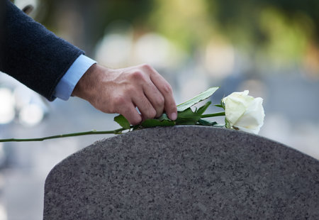 Paying his respects. Cropped shot of a man placing a white rose on a grave.の写真素材