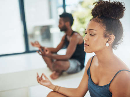 Get your yoga on. Shot of two people doing yoga together in a studio.の写真素材